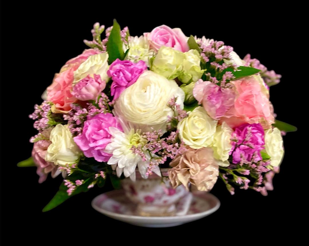 Pink and cream rose bouquet in a teacup on a saucer