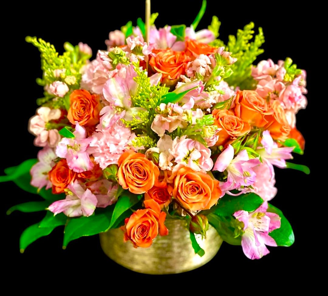 Orange roses and pink flowers arranged in a gold bowl