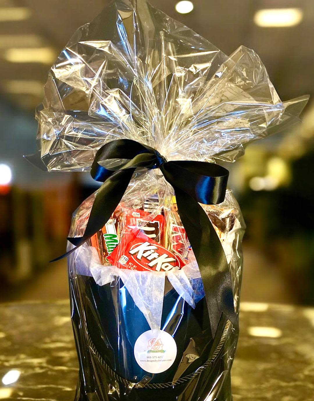 Gift basket with assorted candy wrapped in clear cellophane and a black ribbon