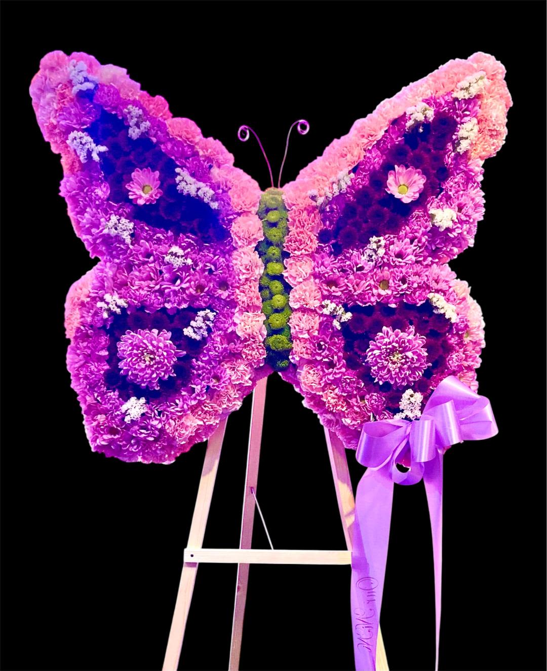 Butterfly-shaped floral display in pink and purple on an easel