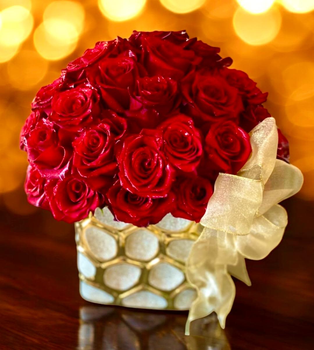 Red rose bouquet in a gold-and-white vase with a cream ribbon