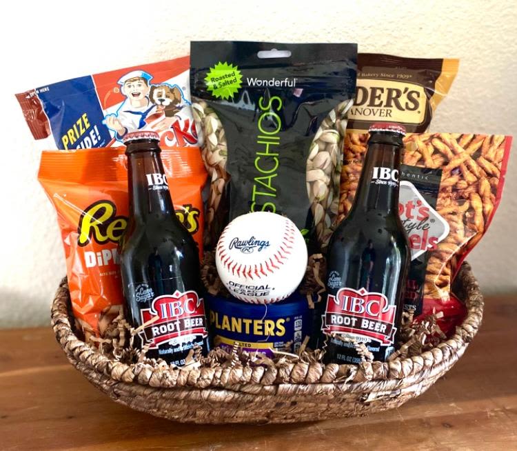 Basket of snacks with two root beer bottles and a baseball