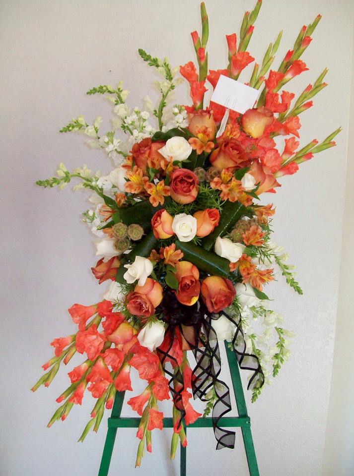 Tall floral standing spray with orange and white roses and red gladiolus