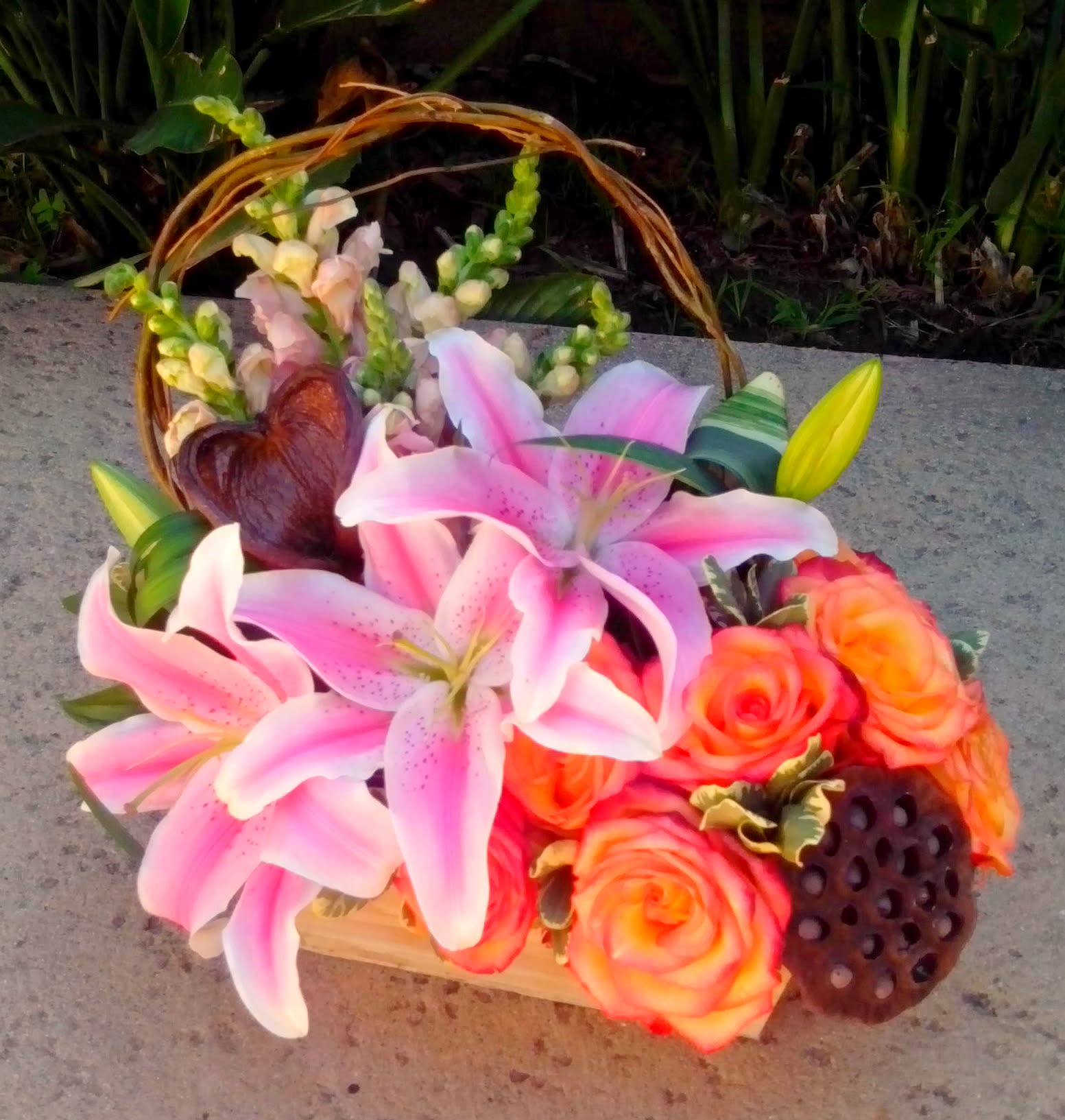 Pink lilies and orange roses in a basket with a woven handle