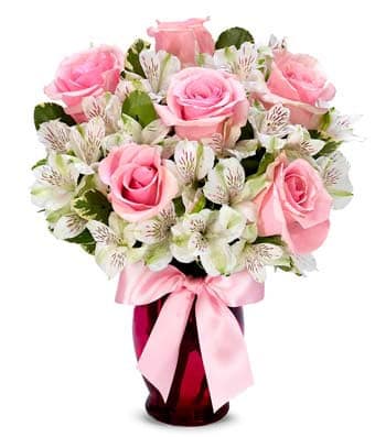 Pink roses and white alstroemeria in a red vase with a pink ribbon