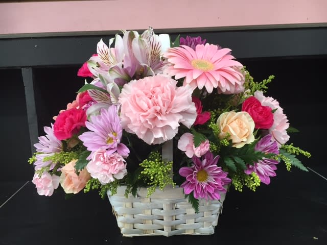 Spring Mix in a Basket - A beautiful mix of Spring flowers hand-crafted in a lovely white wicker basket. Includes some roses, carns, gerbera, and more! A great way to let someone know that you are thinking of them. Great for any occasion!