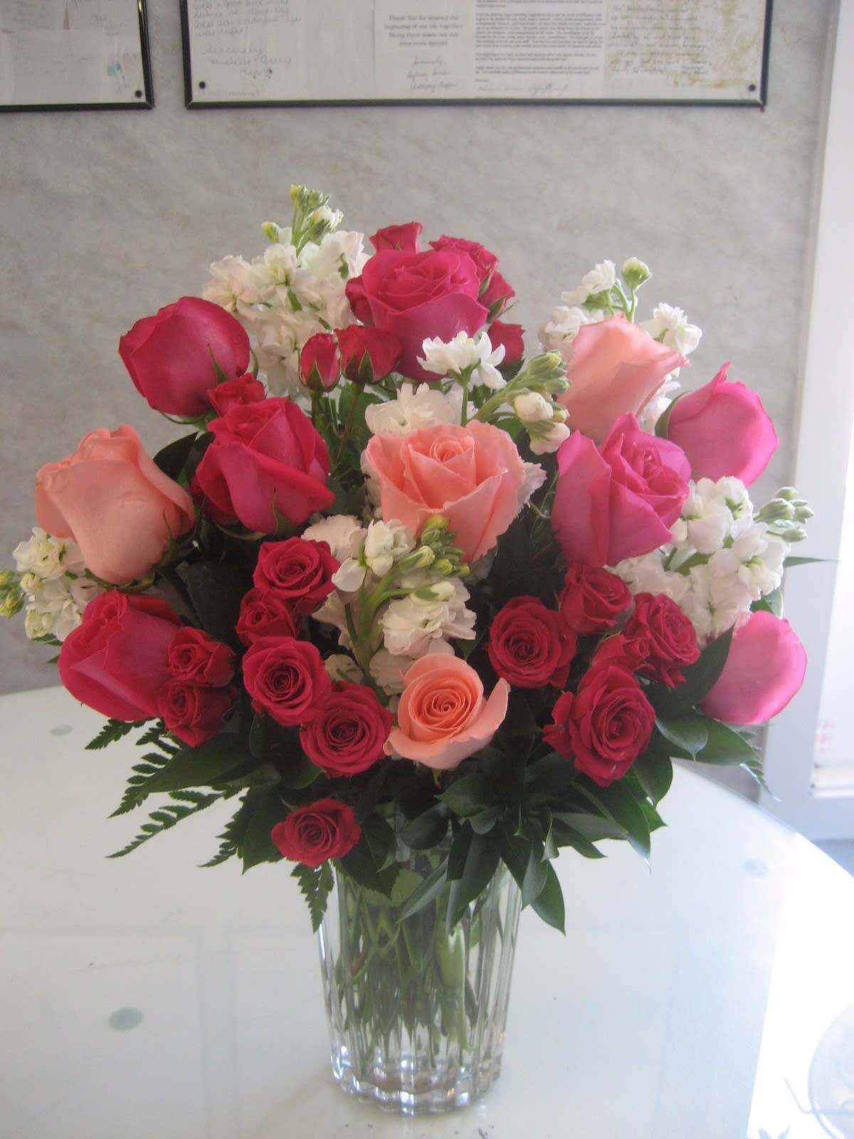 Bouquet of pink, red, and peach roses in a clear glass vase