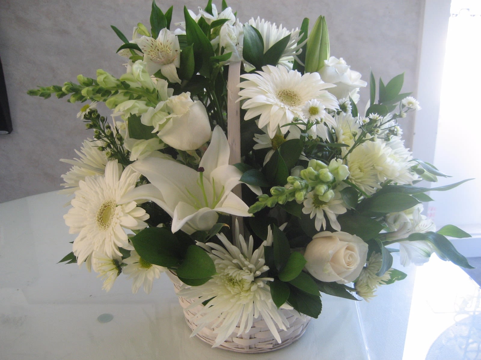 White Wicker Basket Arrangement - A white wicker basket full of white flowers is a great way to send your sympathies to a friend in need. Also makes for a lovely Easter/Passover table arrangement.