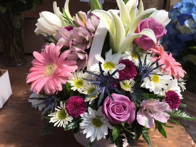 Spring Basket of Happiness - A stunning display of beautiful fresh blooms hand-crafted and designed in a white wicker basket. Makes for a wonderful centerpiece, gift, or even just treat yourself and decorate your home for Spring! Includes a wide array of fresh blooms, gerbera, lilies, roses, and many more!
