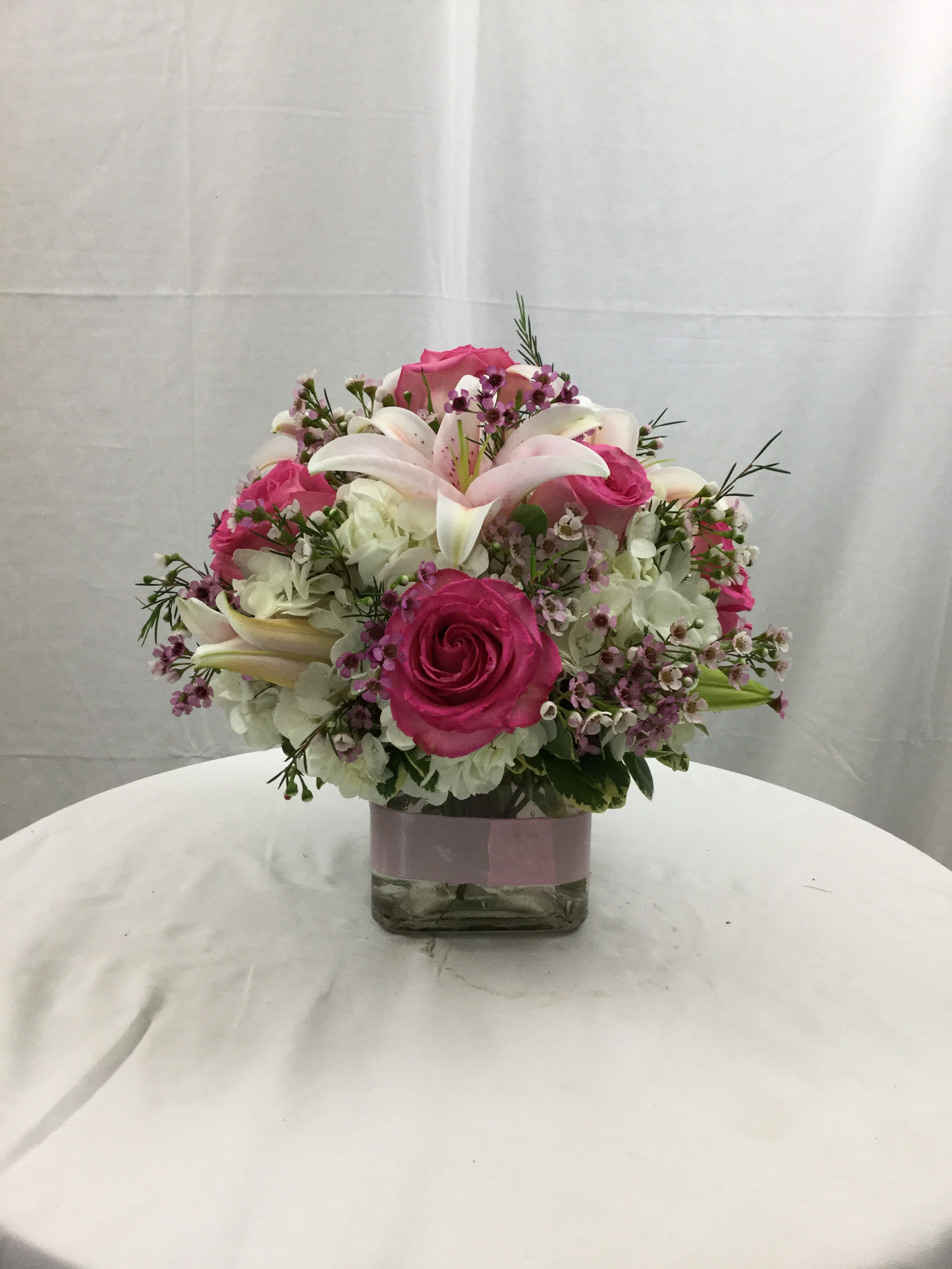 In Love With Spring Cube Bouquet - This beautiful cube bouquet gives off an elegance of love. Makes for a wonderful gift all year long for every special occasion. Please Note: Lilies may come in bud form. When Lilies are at their freshest, they are in bud form. We receive shipments of blooms every single day. 