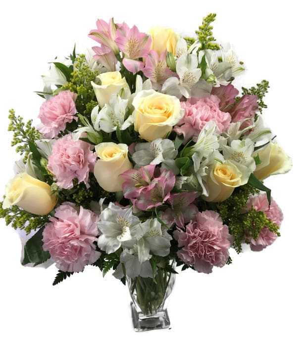 Bouquet of pink and white flowers with pale yellow roses in a clear glass vase