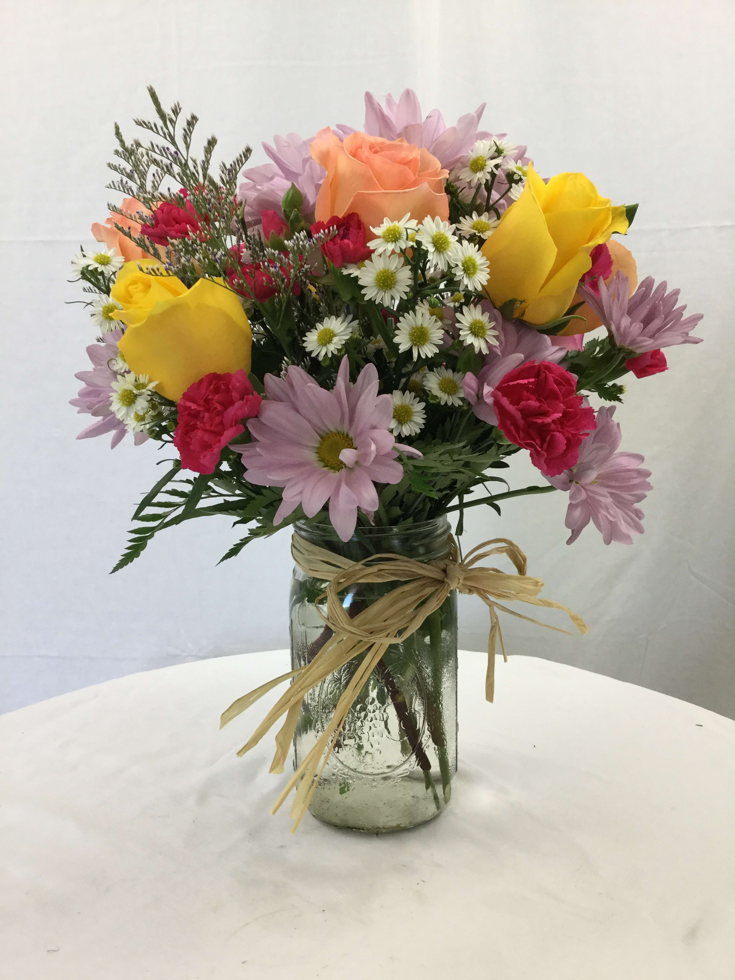 Passionate Spring Bouquet - This stunning bouquet is the perfect gift for any special occasion. This bouquet includes a beautiful mix of fresh blooms, fresh greenery and is handcrafted and designed in a clear glass vase. It's topped off with a raffia bow to create an elegant masterpiece.