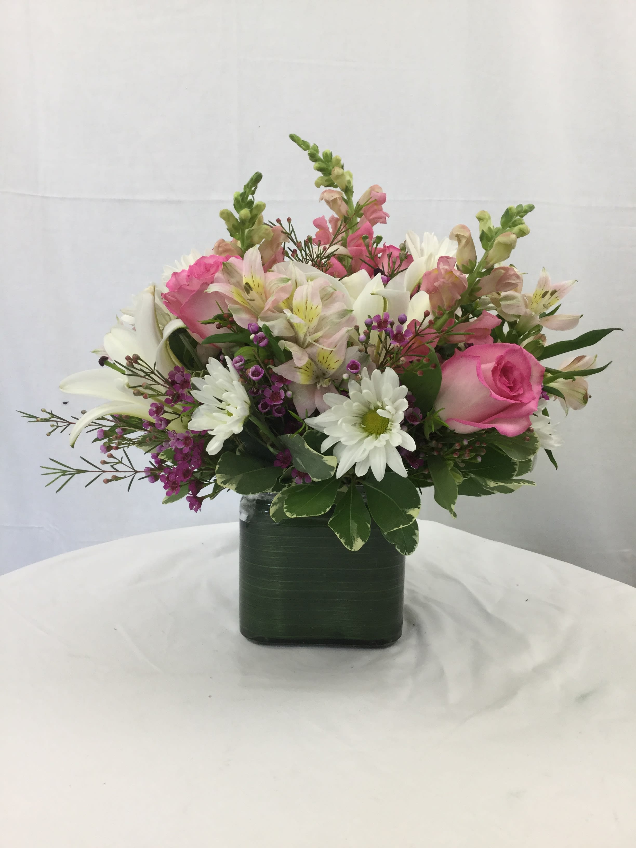 Pink and white mixed flower arrangement in a square vase