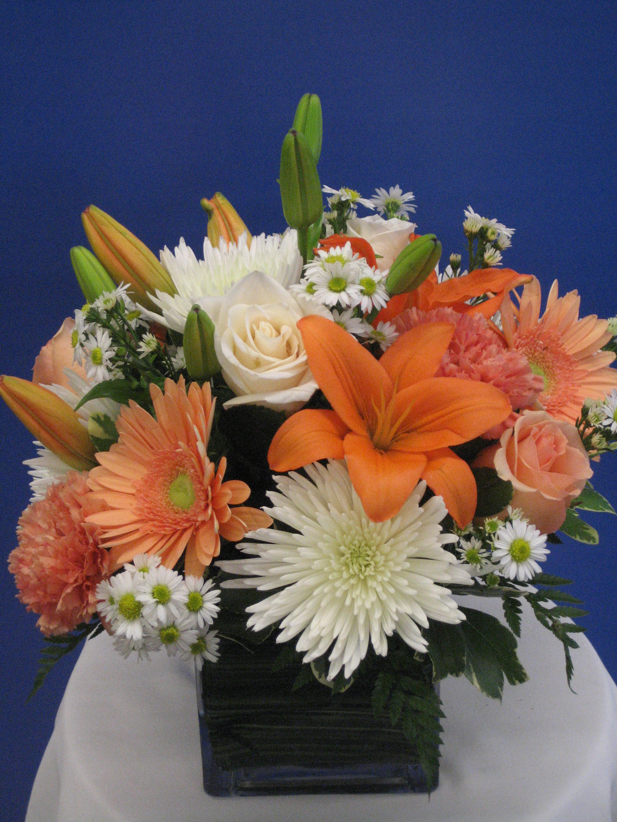 Calming Thoughts Bouquet - This beautiful bouquet is both bold, but soft on the eyes. The white and orange hues send off a very calm and happy vibe. The clear wrapped cube adds a touch of elegance, and the big open flowers pop loud enough to induce a much needed smile. Send to a loved one for any special occasion. Keep in mind, our lilies are delivered to us every single day and may come in bud form per photo. They will open up in a day or two.