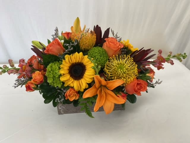 Autumn Love Centerpiece  - This stunning centerpiece is the perfect gift for every special person in your life. Our hand-crafted and designed arrangement is full of fresh Autumn blooms and fresh greens. Decorate a coffee table, a dinner table for Thanksgiving dinner, or make a display on an end table. No matter the use, the recipient will feel the love and warmth of Autumn. 