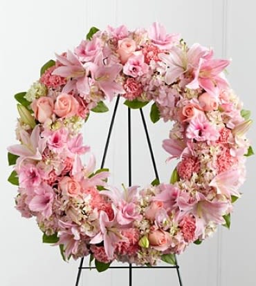 The Loving Remembrance Standing Wreath - The Loving Remembrance™ Wreath is a blushing display of grace and beauty to honor the life of the deceased at their final tribute. Pink roses, Oriental lilies, gladiolus, hydrangea and carnations are brought together with lush greens to form the shape of a wreath, offering warmth and comfort with its sweetly sophisticated elegance. Displayed on a wire easel. Note: Image shown is Premium.
