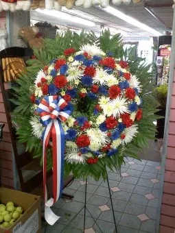 W-9: Patriotic Standing Wreath - Red, White, and Blue Tribute Wreath is handcrafted and designed onto a standing easel. Rich in tradition, this showy standing wreath is sure to make a great impression.