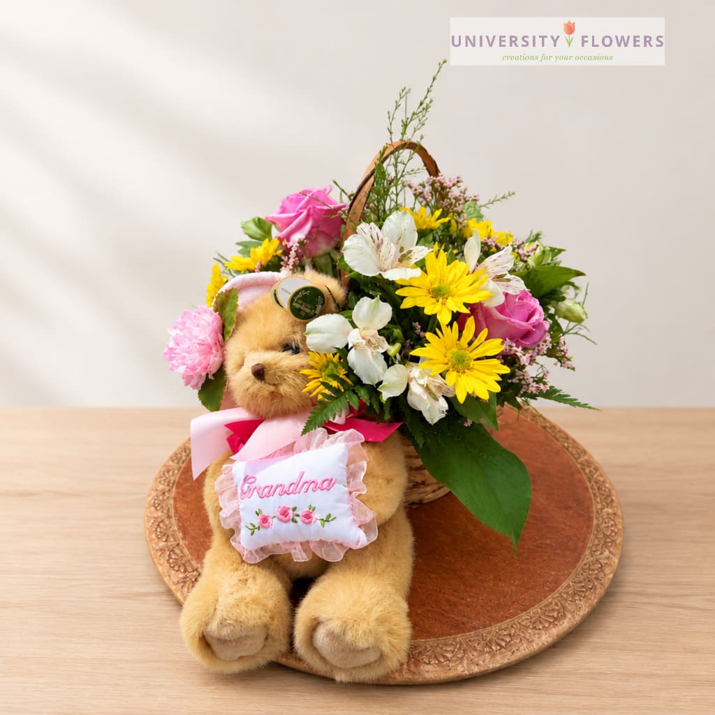 Flower basket with a teddy bear and pink ribbon on a tray
