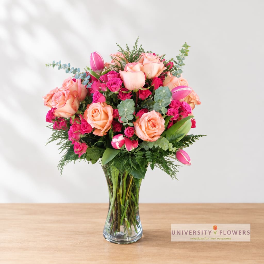 Pink and peach roses with tulips in a clear glass vase