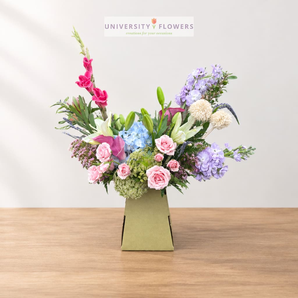 Mixed bouquet in a green box with pink, purple, blue, and white flowers