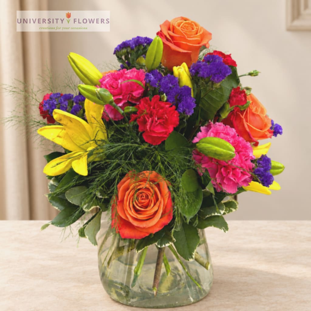 Colorful bouquet of roses, lilies, and carnations in a glass vase