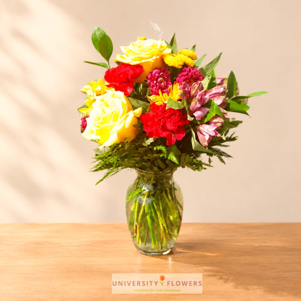 Colorful bouquet of roses, carnations, and alstroemeria in a glass vase
