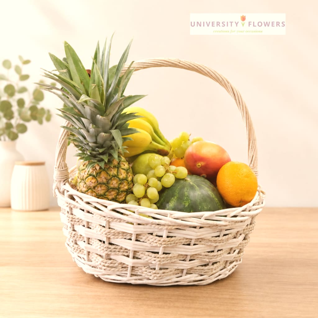 Fruit basket with pineapple, bananas, grapes, mango, melon, and orange in a wicker basket