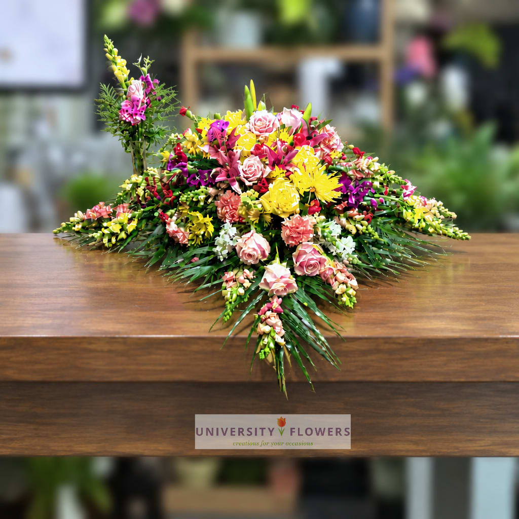 Colorful floral arrangement with pink, yellow, and white blooms on a wooden table