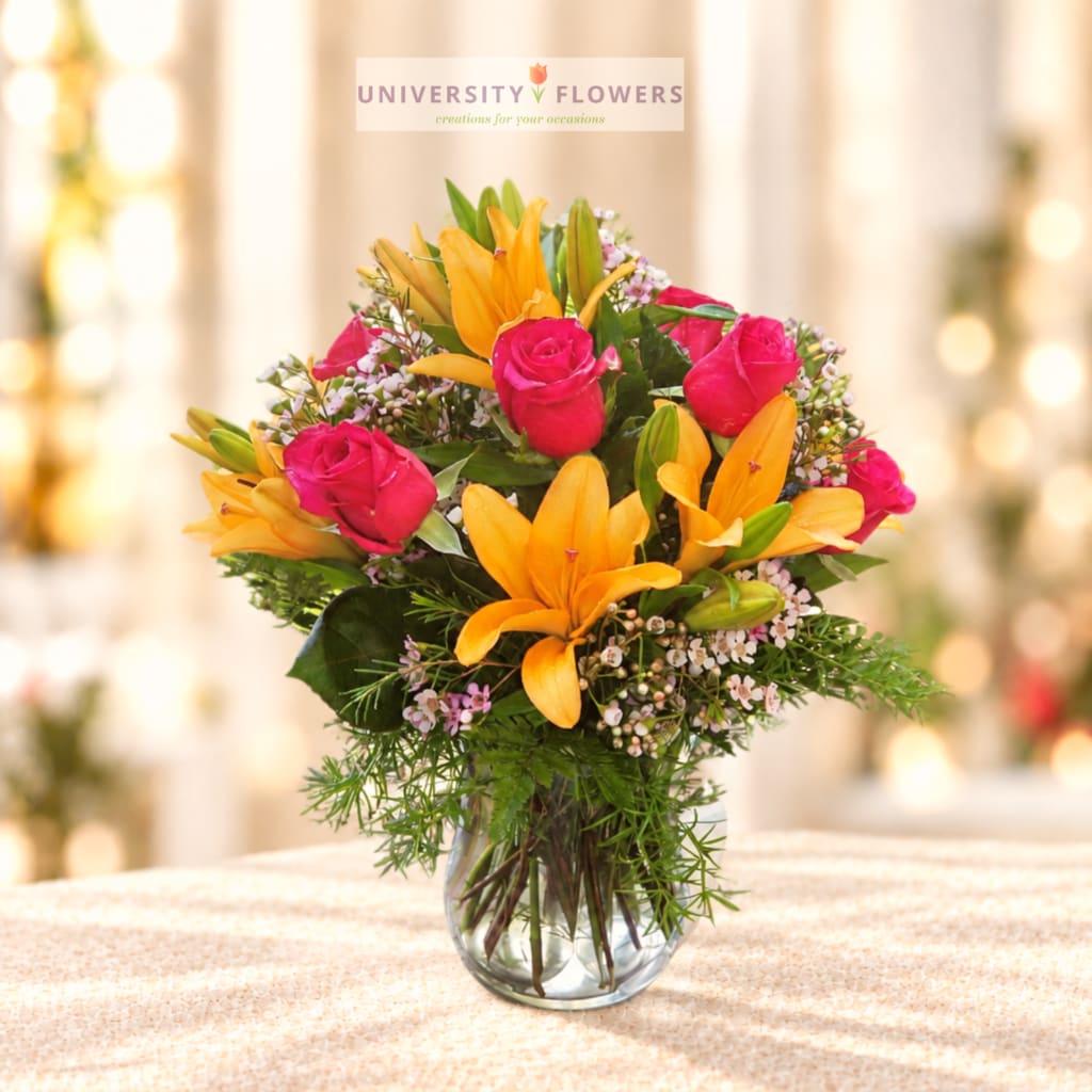 Pink roses and yellow lilies in a clear glass vase