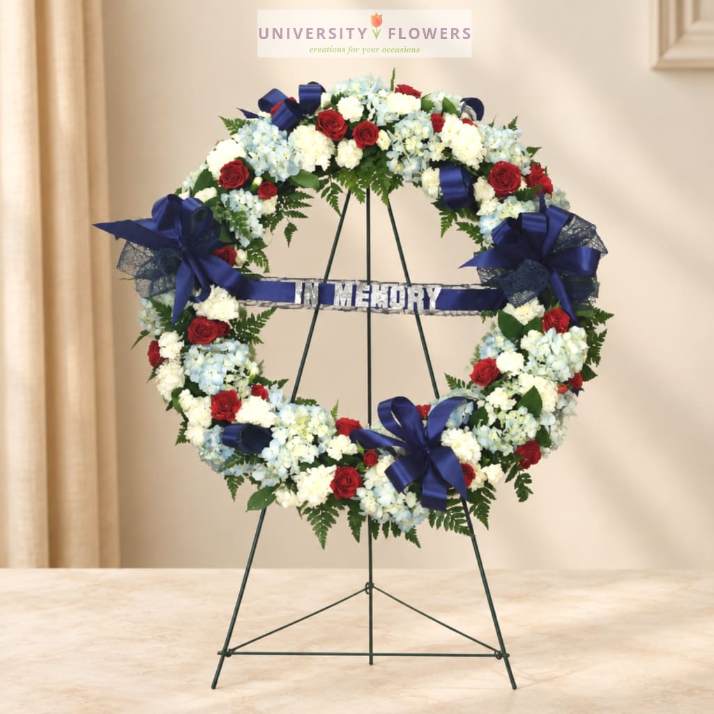 Floral memorial wreath with red, white, and blue flowers on a stand
