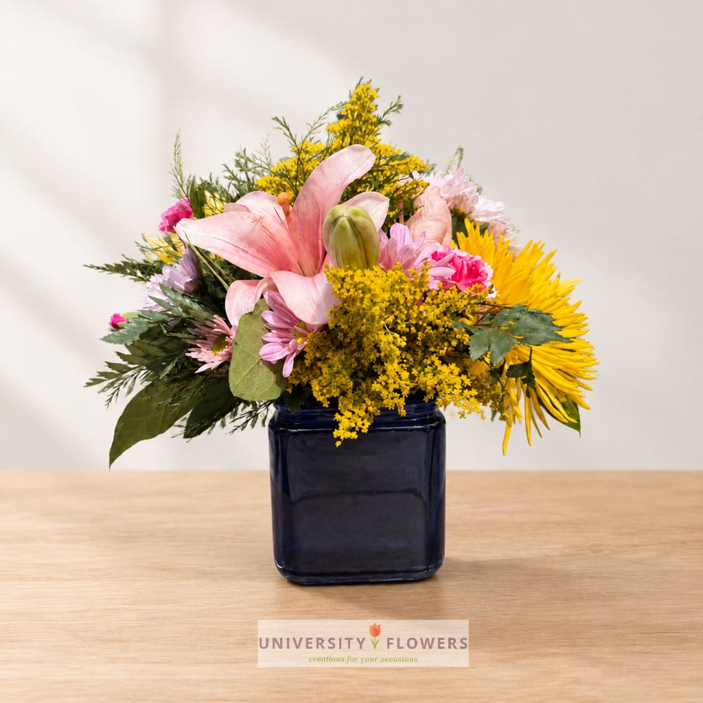 Mixed bouquet in a dark blue vase with pink and yellow flowers
