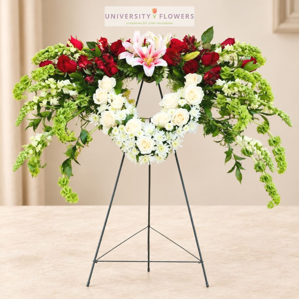 Standing floral wreath with red and white roses and pink lilies on a metal easel