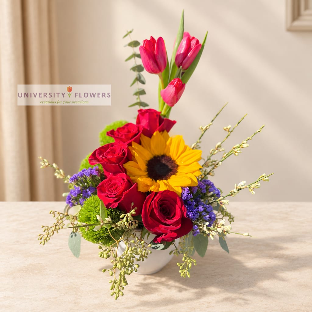Mixed bouquet in a white vase with roses, tulips, and a sunflower