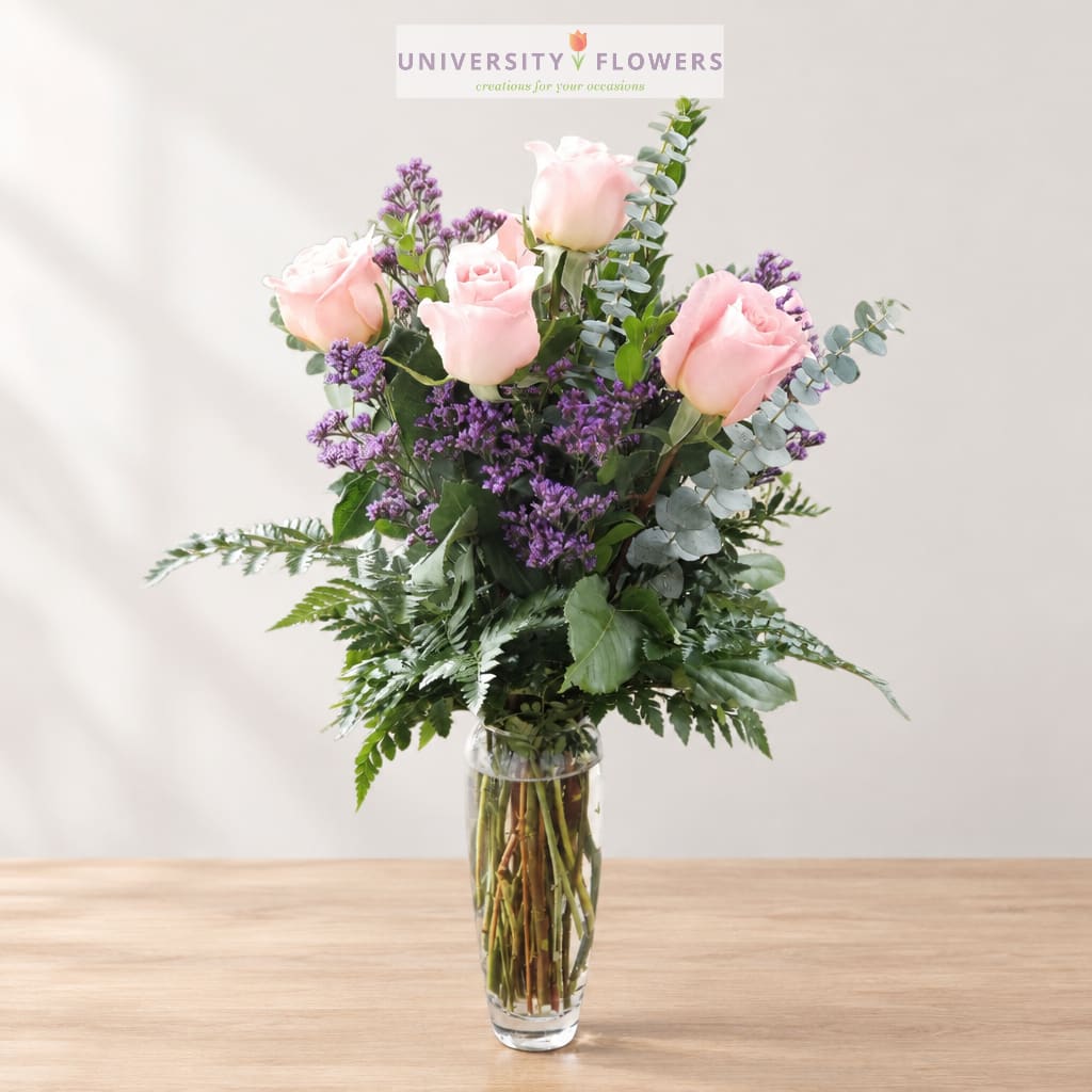 Pink roses and purple filler flowers in a clear glass vase