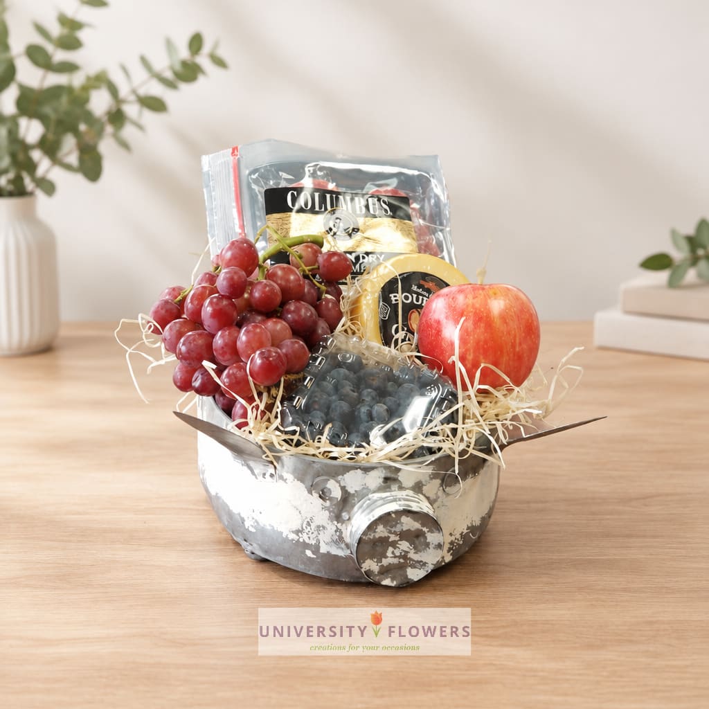 Fruit and snack gift basket in a metal container with grapes, an apple, and packaged treats