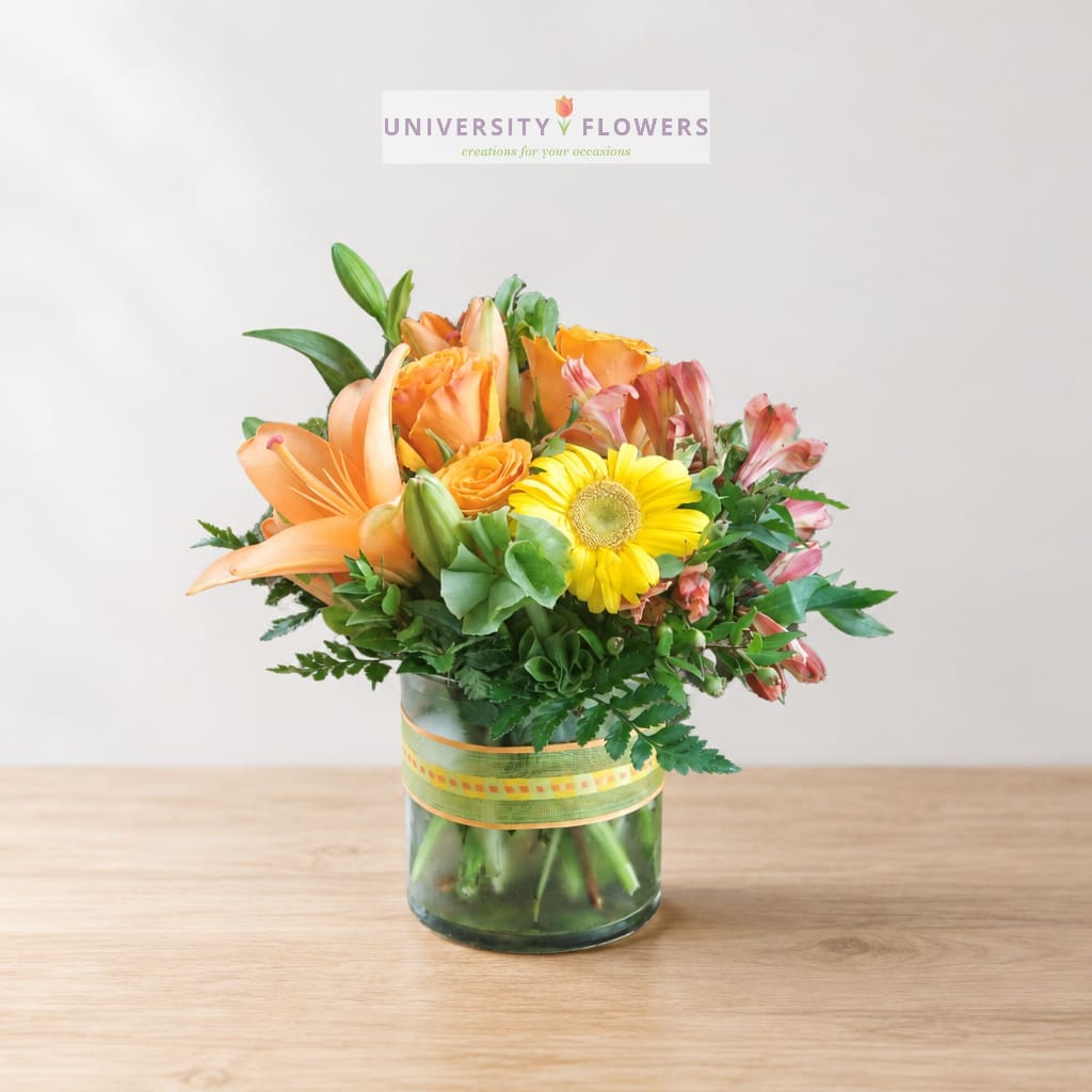 Orange lilies and yellow gerbera daisies in a glass vase