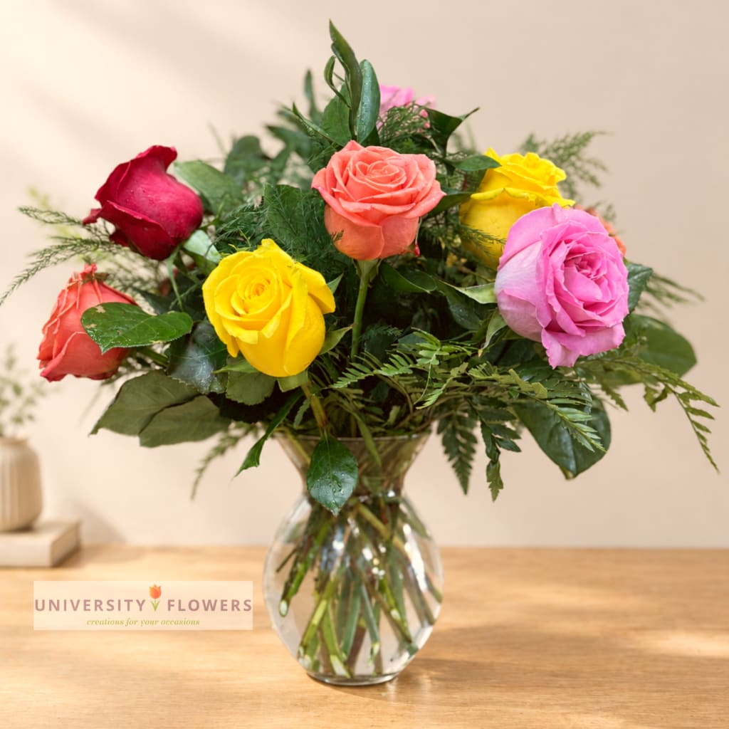 Mixed roses in a clear glass vase on a wooden table