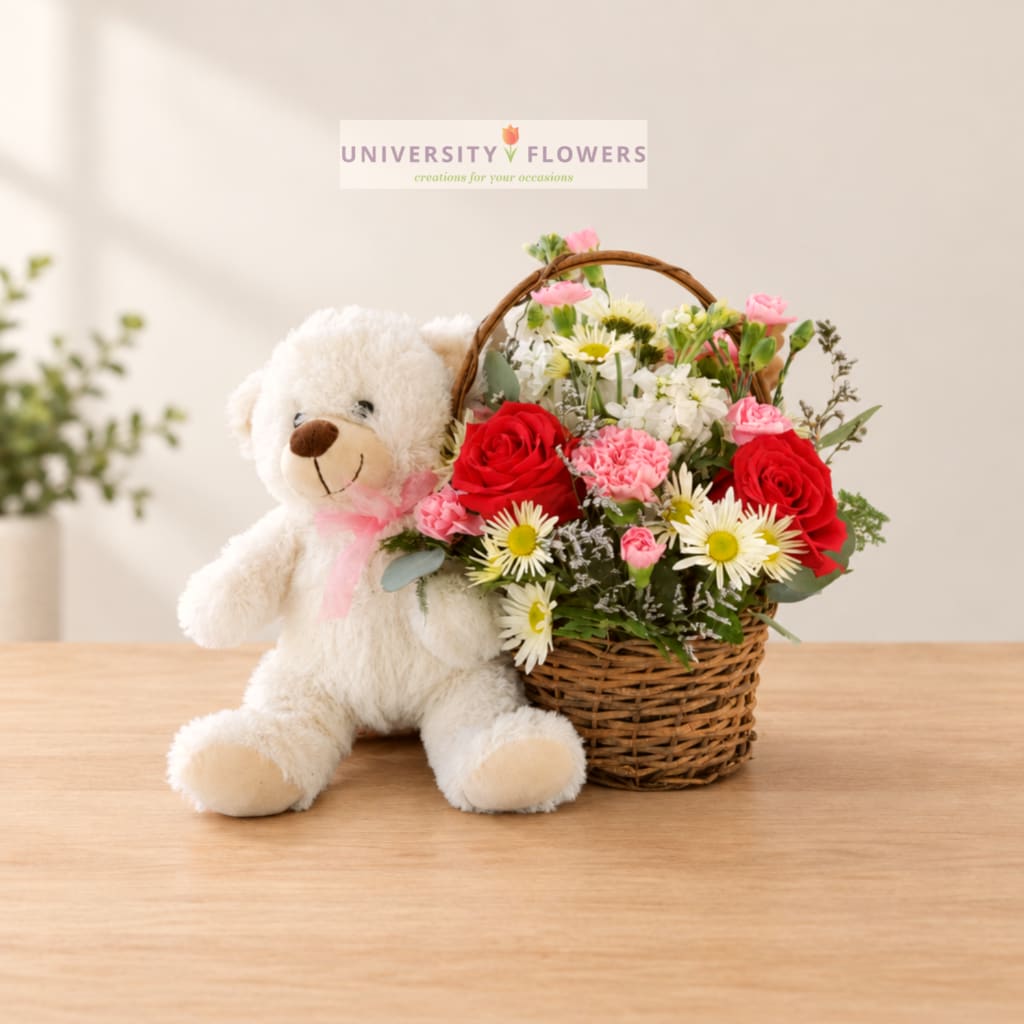 Teddy bear beside a basket of red and pink flowers
