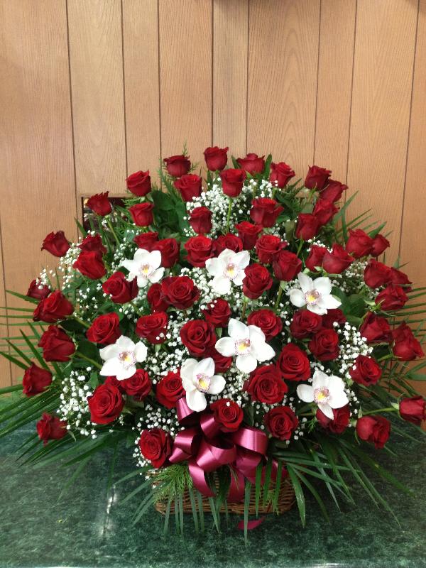Simply Elegant - Sympathy arrangement that is bursting with roses and baby's breath, with a touch of orchids made in a beautiful wicker basket.