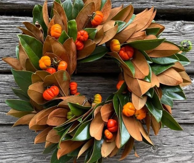 Autumn wreath with green and brown leaves and small orange pumpkins
