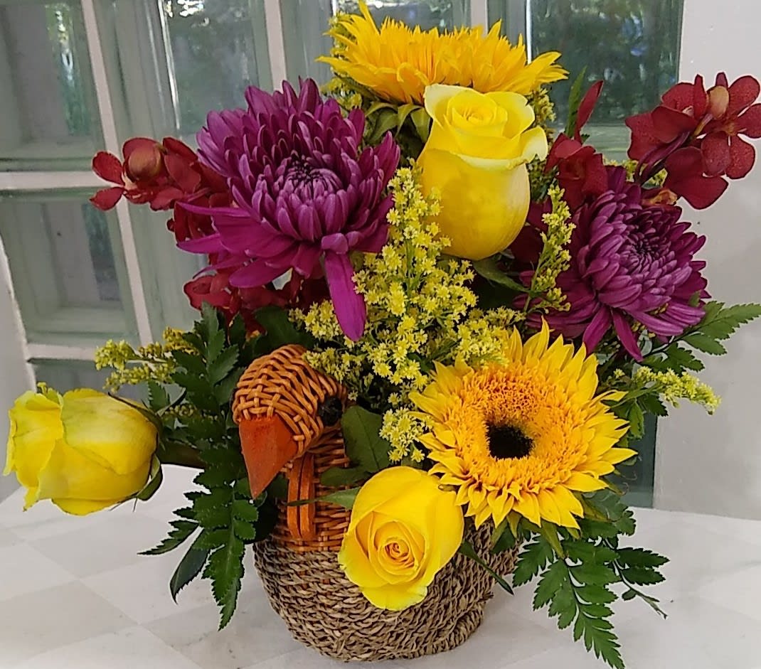 Basket arrangement with yellow roses, sunflowers, and purple chrysanthemums