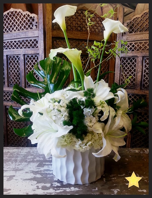White calla lilies and lilies arranged in a white vase