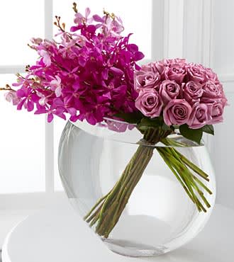 Pink roses and magenta orchids in a clear glass vase