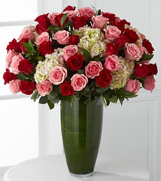 Bouquet of red and pink roses in a tall green glass vase