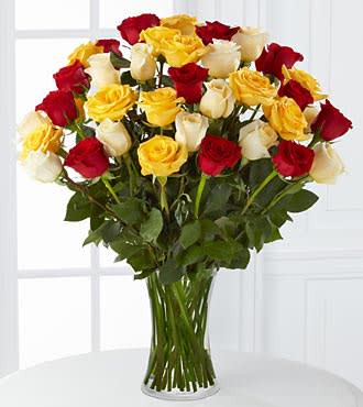 Bouquet of red, yellow, and white roses in a clear glass vase