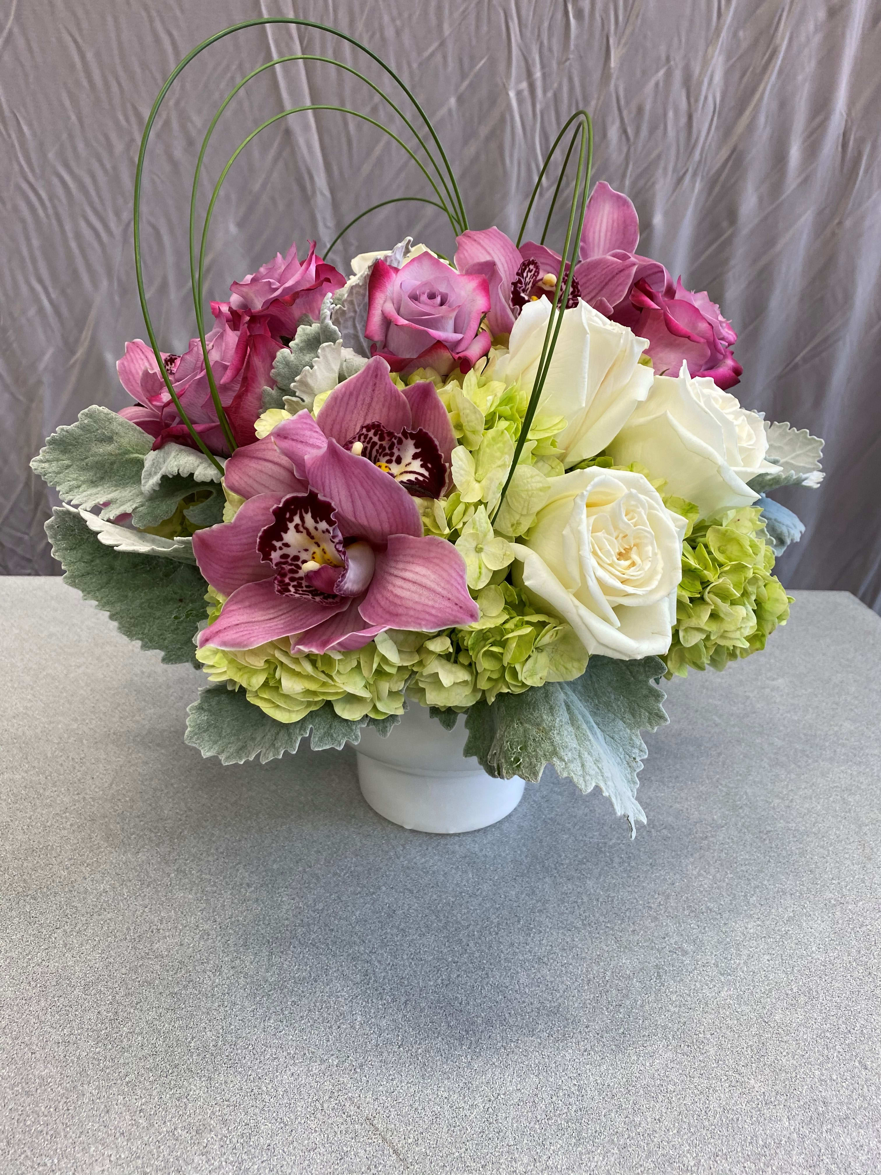 Pink and white floral arrangement in a white vase with arched stems