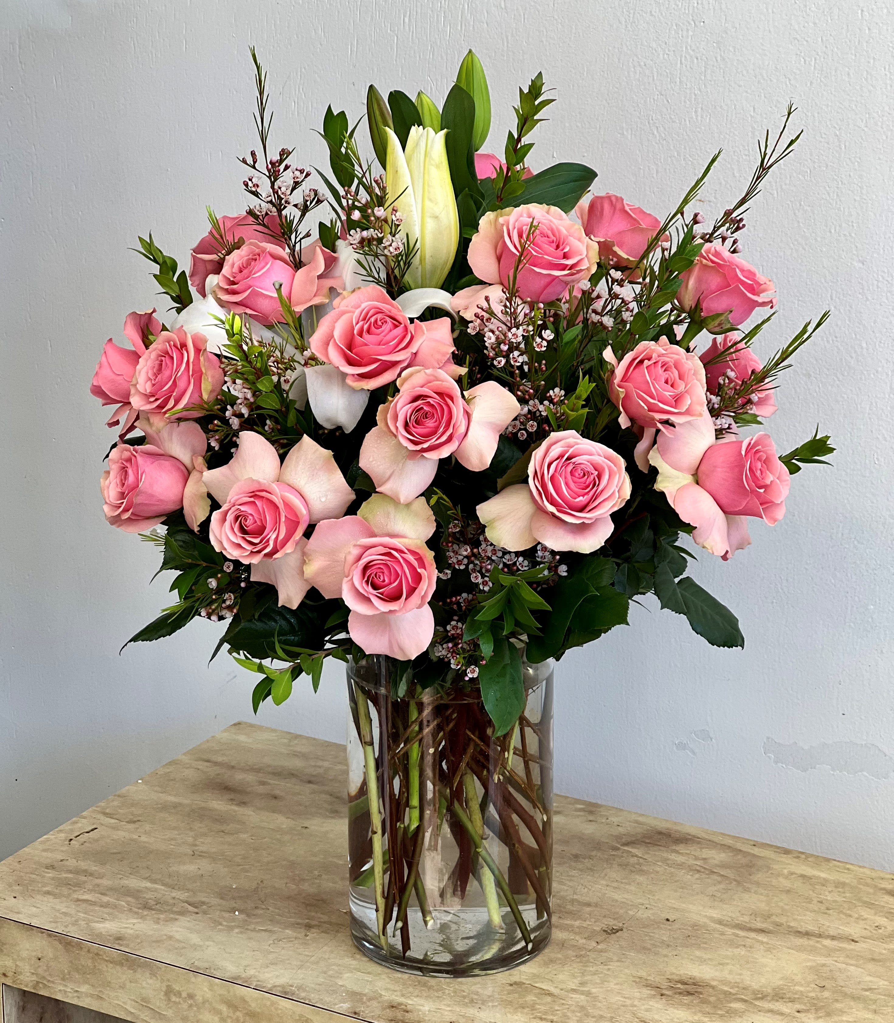 Pink roses and white lilies arranged in a clear glass vase