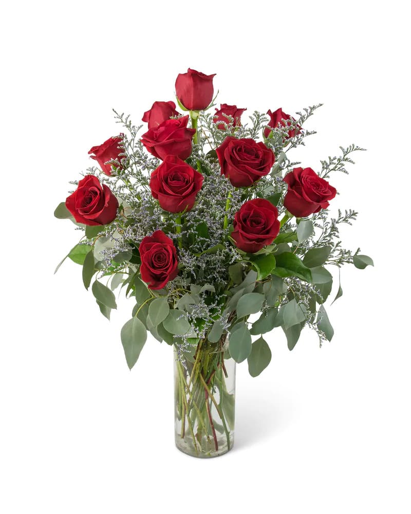 Red roses arranged in a clear glass vase with airy filler and greenery