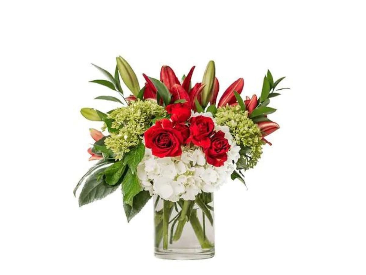 Bouquet of red roses, white hydrangeas, and lilies in a clear glass vase