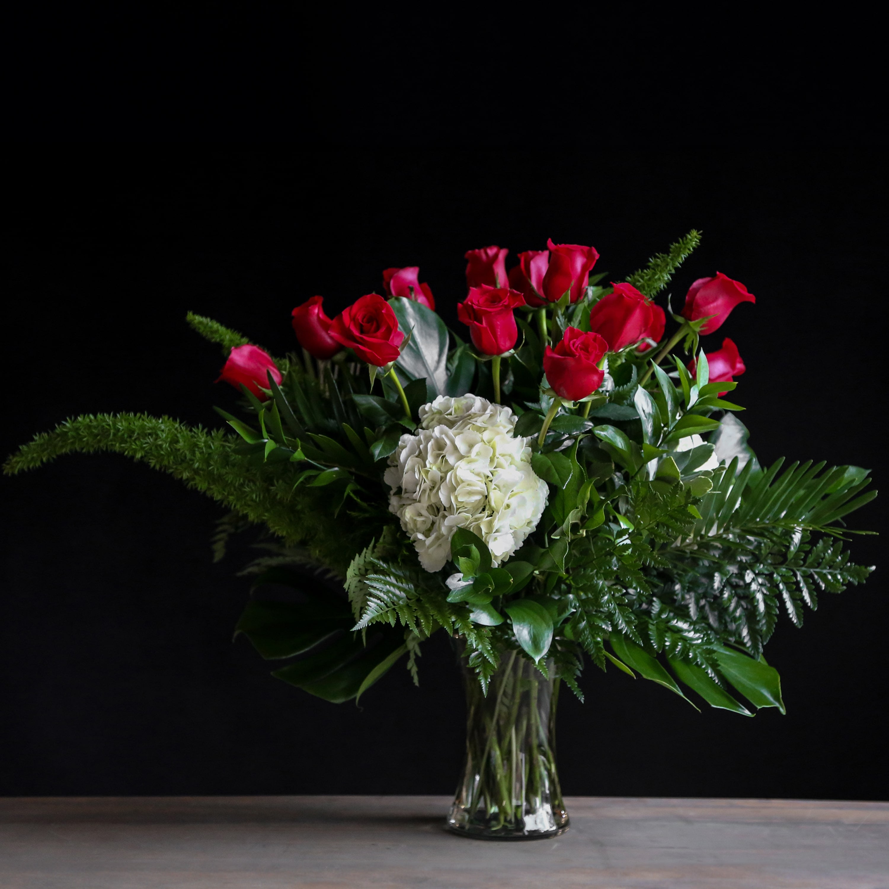 Red roses and white hydrangea in a clear glass vase